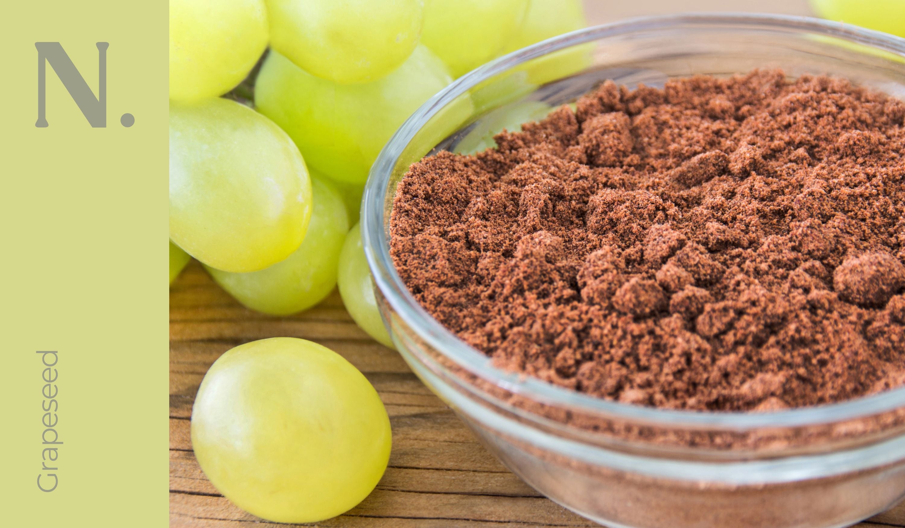 Glass bowl of grape seed with green grapes on the side on a wooden surface - Grapeseed