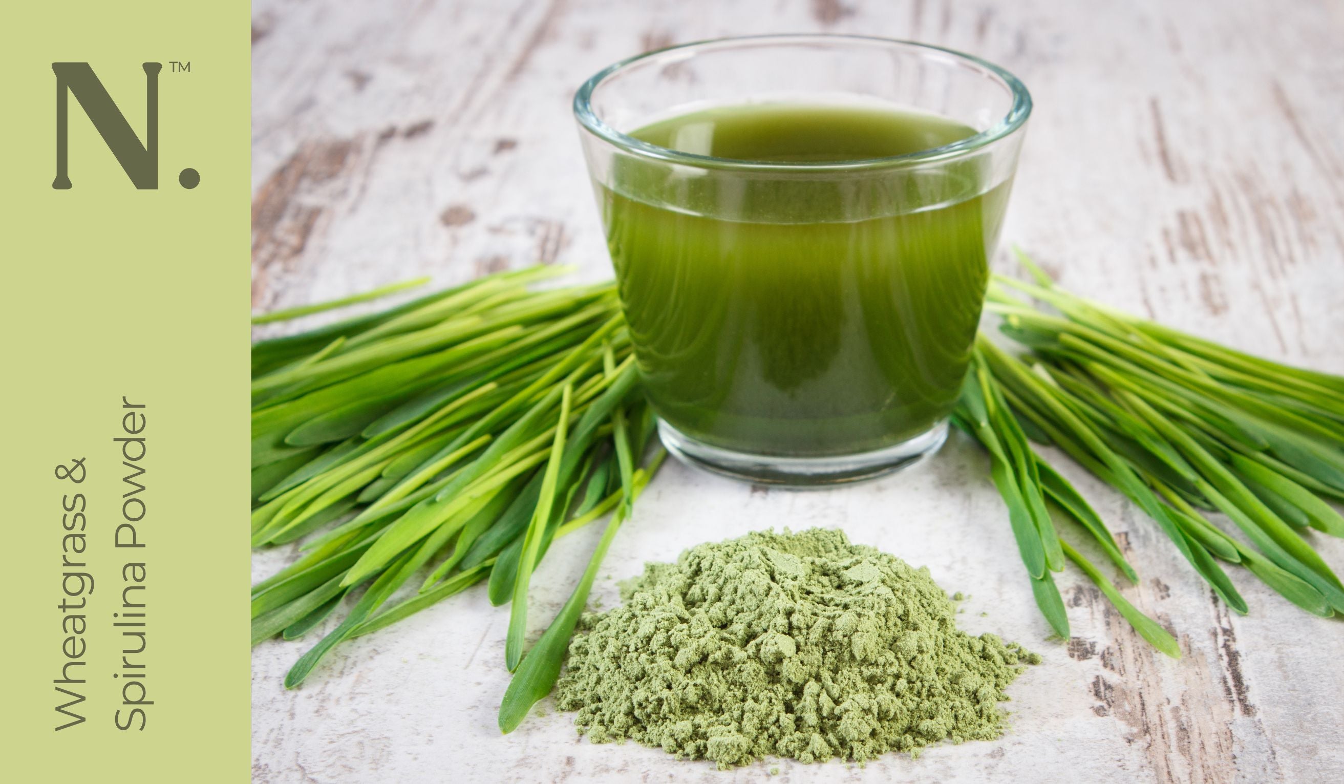 Glass with green liquid in it with wheatgrass and spirulina powder on white wooden surface - Wheatgrass & Spirulina